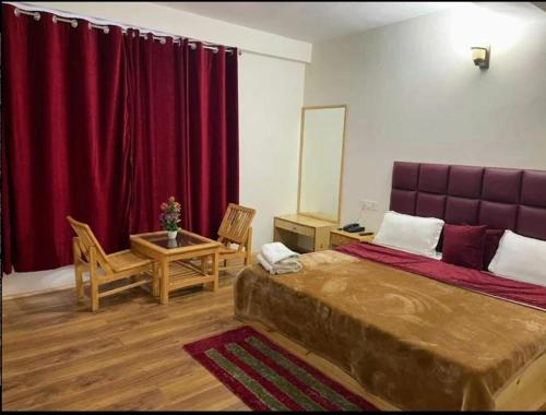 een slaapkamer met een groot bed en rode gordijnen bij New Chandra Bhaga Guest House in Manāli