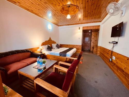 a living room with a bed and a couch at Manali Heritage Hotel in Manāli