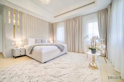 a white bedroom with a bed and a table at Luxury 3BR Villa with Assistant Room at Alvorada 4 Arabian Ranches by Deluxe Holiday Homes in Dubai