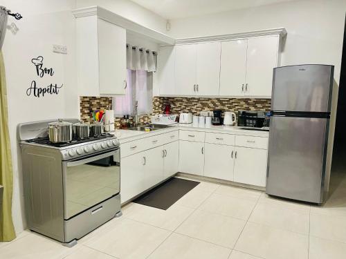 a kitchen with white cabinets and a stainless steel refrigerator at SALT ST LUCIA in Vieux Fort