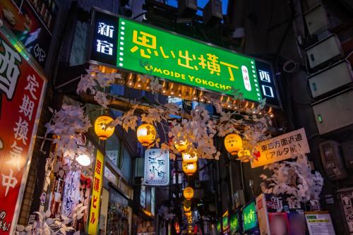 APA Hotel - Higashishinjuku Kabukicho Higashi في طوكيو: شارع المدينة مزدحم ليلاً مع لافتات النيون
