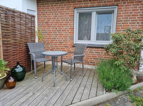 een patio met 2 stoelen, een tafel en een raam bij Fewo Neuruppin Einliegerwohnung in Neuruppin