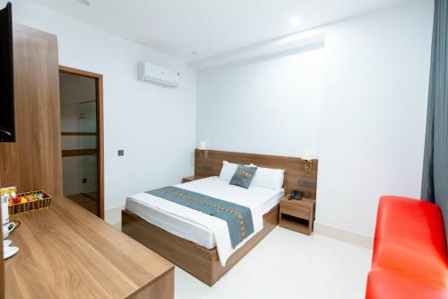a bedroom with a bed and a red chair at Khách sạn Vạn Phúc - Yên Bái in Xóm Soi (2)