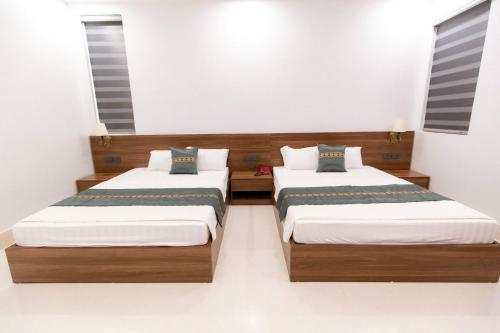 two beds in a room with white walls at Khách sạn Vạn Phúc - Yên Bái in Xóm Soi (2)
