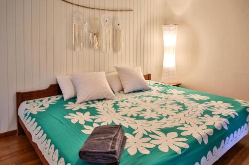 a bedroom with a large bed with a green and white blanket at Charmante villa familiale, piscine vue imprenable in Pirae