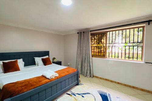 um quarto com uma cama grande e uma janela em Cozy Living by Miranda, Acacia - 2 BDR, 4 beds, 3 Bthrms, Unlimited WIFI, Free Parking, Netflix em Kampala