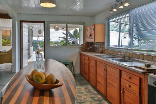 a kitchen with a bowl of fruit on a wooden counter at Charmante villa familiale, piscine vue imprenable in Pirae