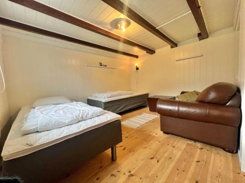 a room with two beds and a leather couch at Lofoten Fjord Apartment - Kvalvika Beach & Ryten in Skjelfjord