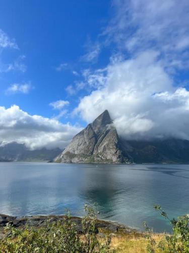 a mountain in the middle of a large body of water at Lofoten Fjord Apartment - Kvalvika Beach & Ryten in Skjelfjord