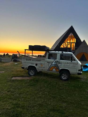 a white jeep parked in a field in front of a building at Lofoten Fjord Apartment - Kvalvika Beach & Ryten in Skjelfjord