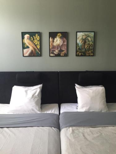 two beds in a room with four paintings on the wall at Västerviks Citylägenhet in Västervik