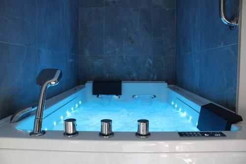 a blue tub with a faucet in a bathroom at Belle maison normande avec hamam sauna jacuzi in Saint-Pierre-de-Cormeilles