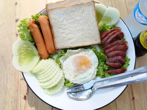 um prato de alimentos com ovos, salsichas e legumes em Cool Pool Bungalow em Ban Phônmuang