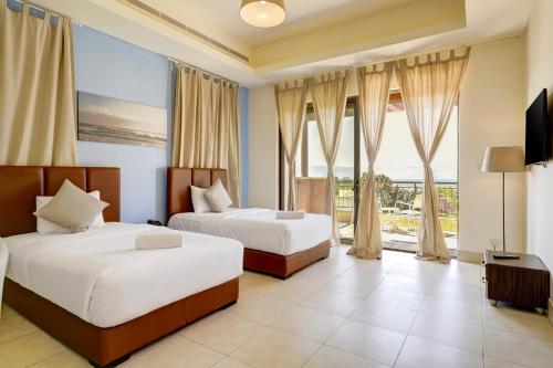 a bedroom with two beds and a large window at Shoreline Apartment - Tala Bay in Aqaba