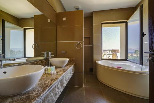 a bathroom with two sinks and a tub and windows at Shoreline Apartment - Tala Bay in Aqaba