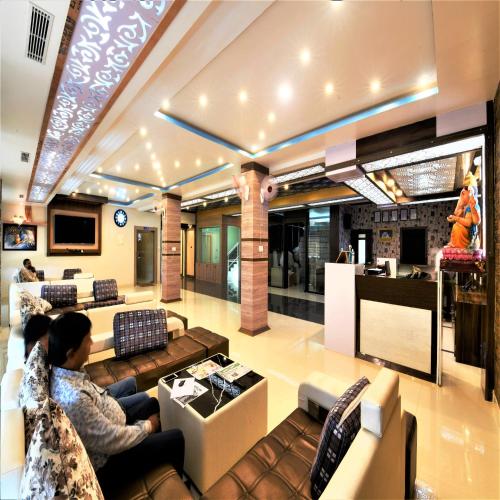 two people sitting on couches in a living room at Hotel Star Bodh Gaya in Bodh Gaya