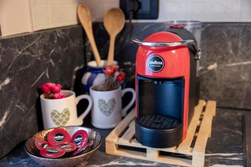 a red coffee maker on a wooden stand next to cups at 203 Aosta Apartment in Aosta