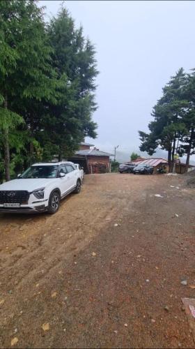 a white car parked in a dirt parking lot at BLACKVILLA in Mukteswar