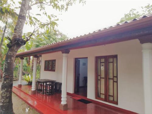 a small white house with a table in front of it at Qiqi beach house in Weligama