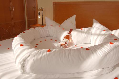 a white bed with a bottle of champagne in a snolicited at Pension Sanddorn mit Café Carlssons in Binz