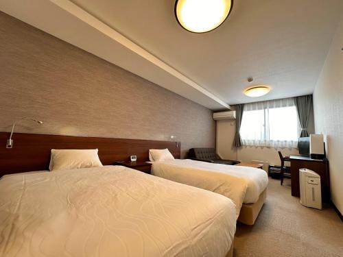 pokój hotelowy z 2 łóżkami i telewizorem w obiekcie Hotel Togariishi w mieście Chino
