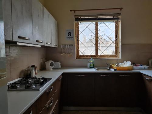 a kitchen with a stove and a sink and a window at EEM student Guest House (shared rooms) in Is-Swieqi