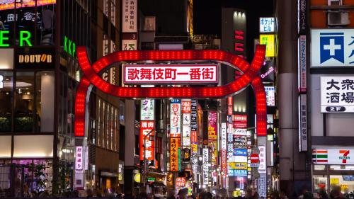 東京にあるアパホテル〈新宿 歌舞伎町タワー〉のネオンの看板が立つ賑やかな街道