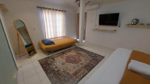 Cette chambre comprend une chaise, une télévision et un tapis. dans l'établissement Sea La Vie, à Pangandaran