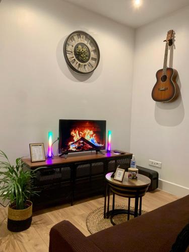 een woonkamer met een tv en een gitaar aan de muur bij L'Industriel : Duplex Montreuil in Montreuil