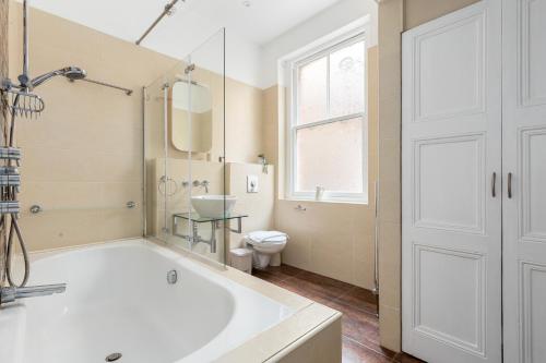 a bathroom with a tub and a toilet and a window at The Chiswick Apartments in London