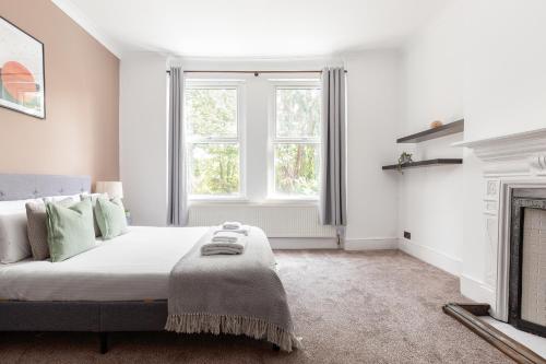 a white bedroom with a bed and a fireplace at The Chiswick Apartments in London