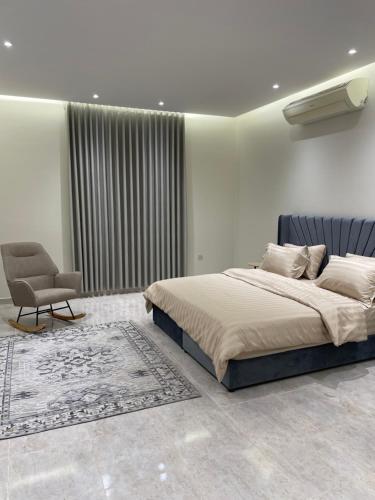 a bedroom with a large bed and a chair at شقة غرفتين وصالة مدخل خاص باركنج سيارة in Riyadh Al Khabra