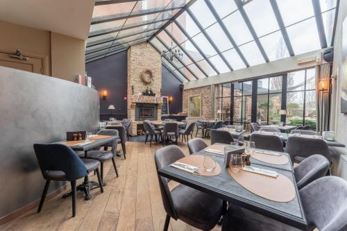 um restaurante com mesas e cadeiras e um tecto de vidro em Maison de la Paix em Poperinge