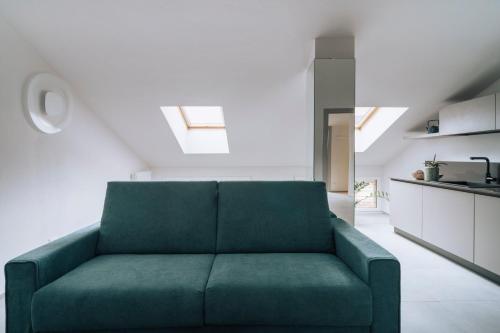 a green couch in a room with a kitchen at Aosta Holiday Apartments - Monte Solarolo in Aosta