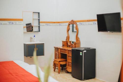 a room with a refrigerator and a desk and a tv at VILLA GIÓ BIỂN LAGI - Villa Gia đình 4 Phòng Ngủ, Sức chứa 8 - 20 Khách, Cách Biển Cam Bình 700m di chuyển, Sân Vườn Rộng Rãi, Tiện Nghi Nướng BBQ & Bãi Đậu Xe Ô tô Miễn Phí in La Gi