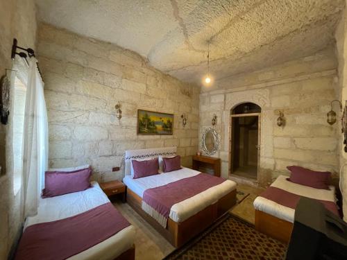 a bedroom with two beds and a stone wall at DEDE CAVE KONAk in Urgup