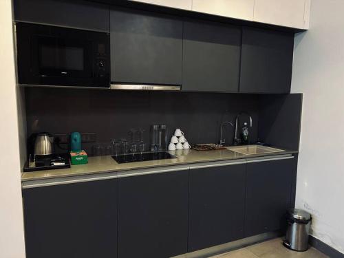 een zwarte keuken met een wastafel en een magnetron bij Luxuria Studio Apartment in New Delhi