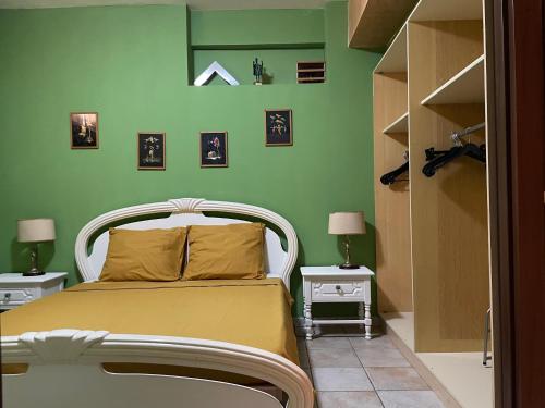 a bedroom with a white bed and green walls at Residence Don Turi in Villafranca Tirrena