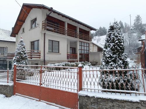 a house with a fence in the snow at Самостоятелна къща за гости Рилски кът Маджаре in Madzhare