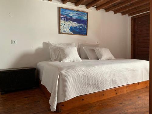 a bedroom with a white bed with a picture on the wall at Traditional apartment in the heart of Mykonos! in Mikonos