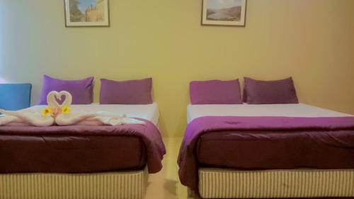 duas camas num quarto com lençóis roxos e brancos em New Tauns Hotel em Klang