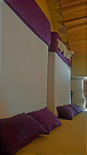 uma cama num quarto com lençóis roxos e almofadas roxas em New Tauns Hotel em Klang