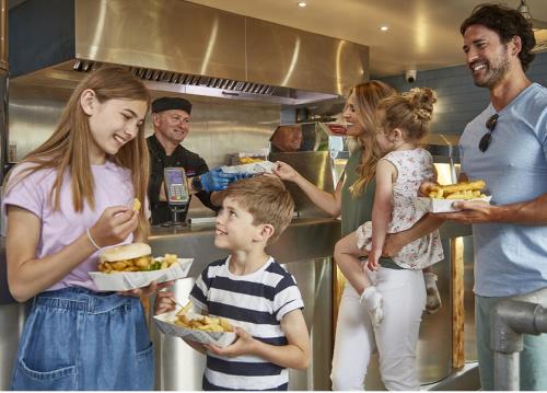 a group of people standing in a kitchen eating food at 51 Oaklands thorness bay Parkdean holiday resort in Cowes