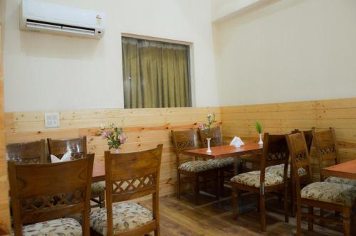een eetkamer met houten tafels en stoelen bij Hotel house inn suite in Noida