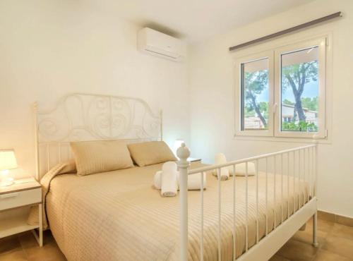 a white bedroom with a bed and a window at Apartamentos Los Pinos in Cala Murada
