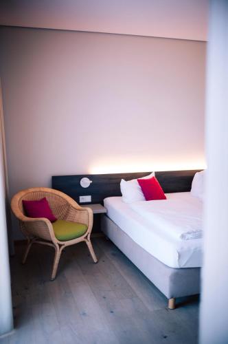 a hotel room with two beds and a chair at Hotel Calamus - 4 Sterne Superior in Kehl am Rhein