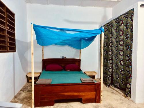 Cette chambre comprend un lit à baldaquin bleu. dans l'établissement Amistad, à Ouidah