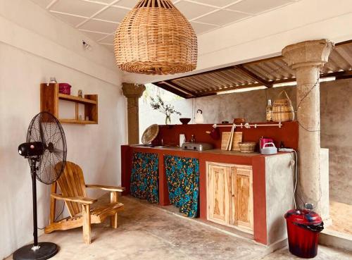Il comprend une cuisine équipée d'une table, d'une chaise et d'un ventilateur. dans l'établissement Amistad, à Ouidah