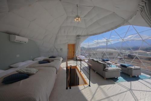 a living room with couches and a large window at Glamping Dome YOSHIMURA in Fujikawaguchiko