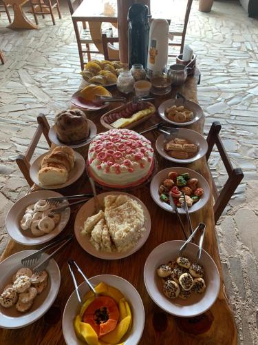 a table full of different types of pastries on plates at POUSADA FAZENDA PAIM in São José dos Ausentes
